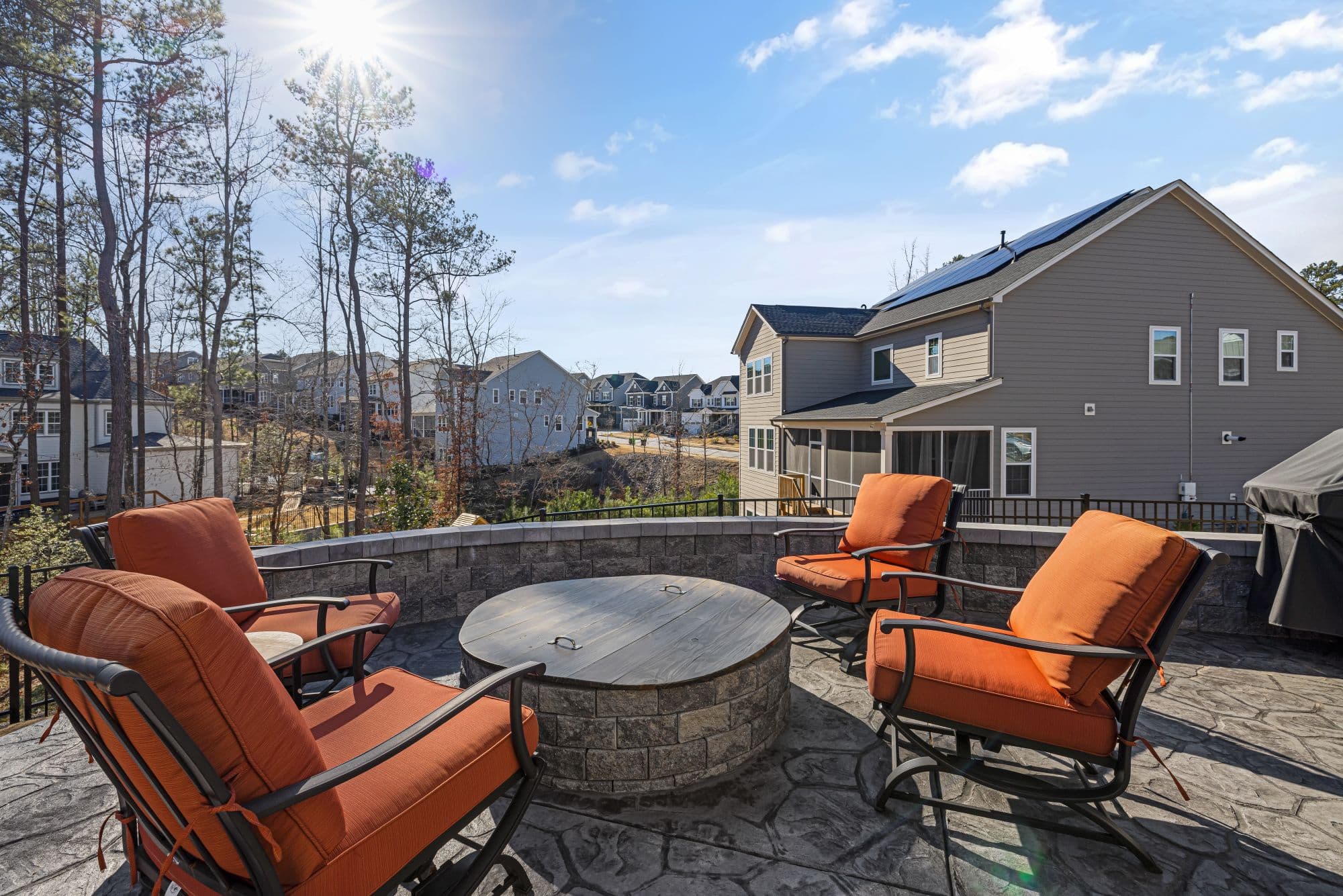 Stone patio with a built-in fire pit overlooking a residential neighborhood