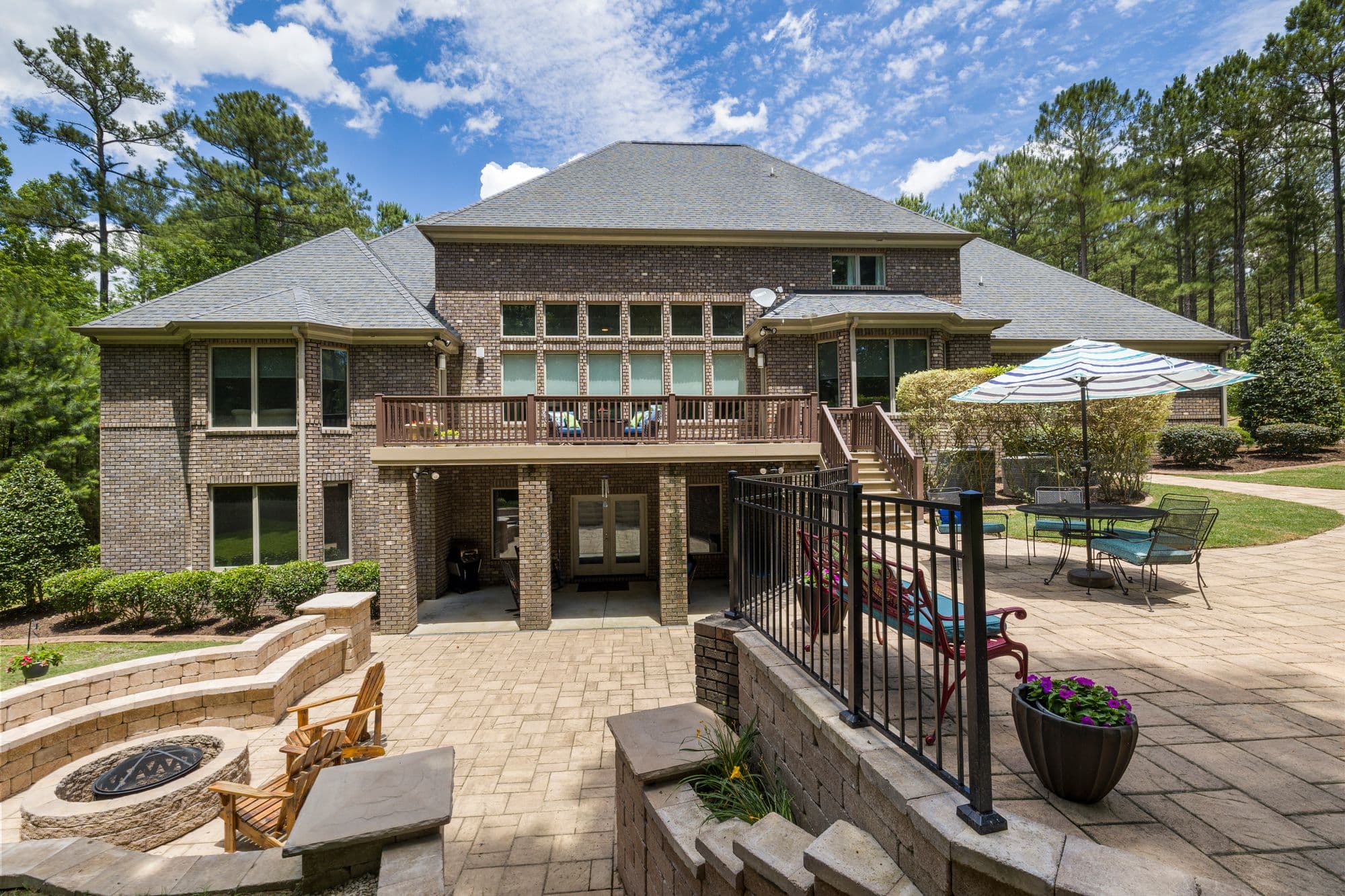Luxury landscaped property with a stone terrace, fire pit, and manicured garden
