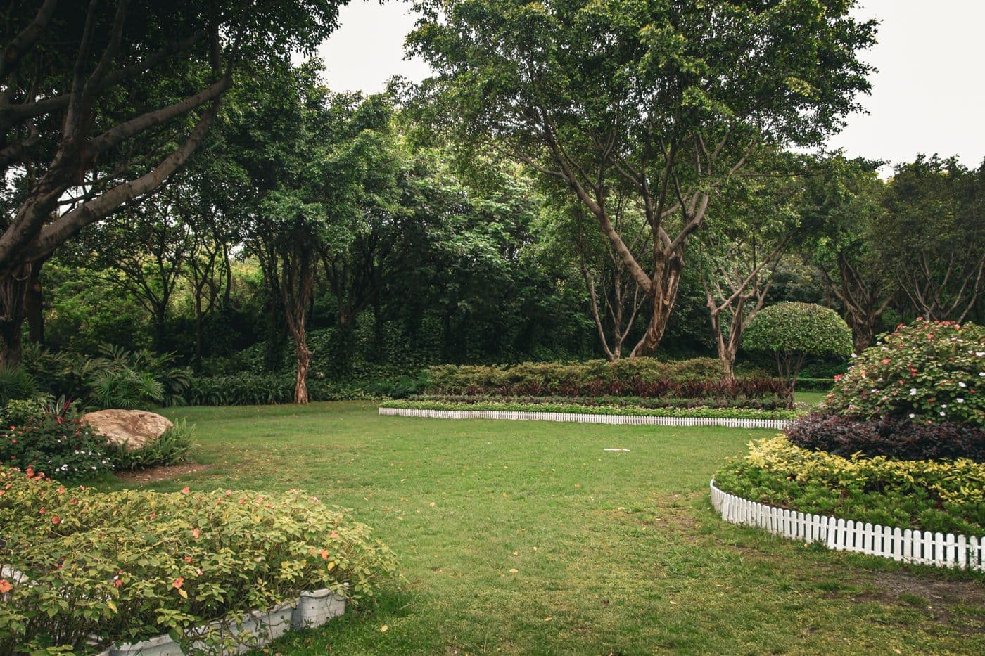 Manicured lawn framed by trees and flower beds